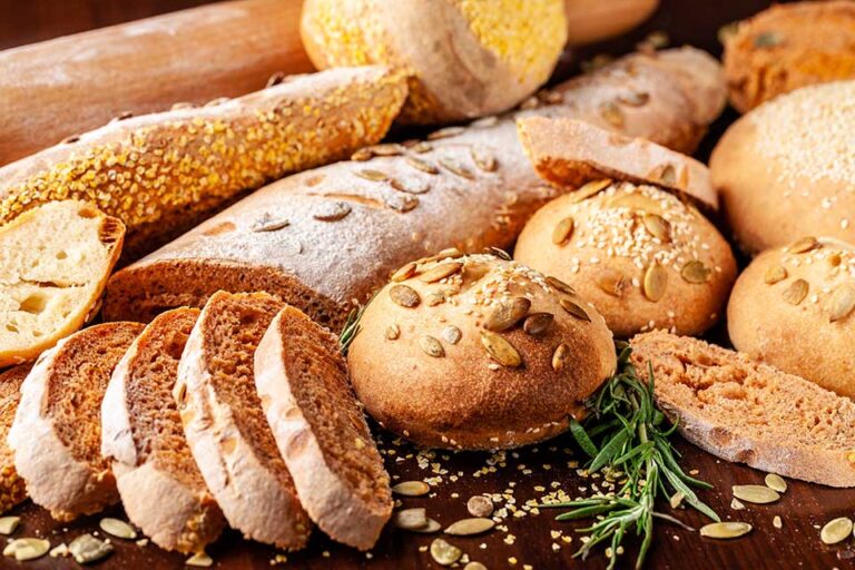 Homemade wholemeal tomato bread with basil and pumpkin seeds, baguette, buns, lie on a wooden table. Background image